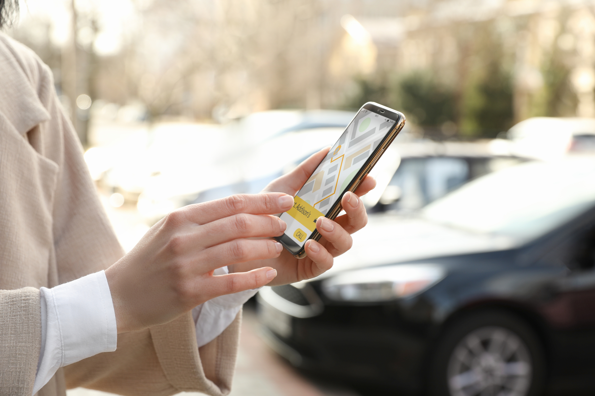 Navigation & Hands Free Tech - Woman ordering taxi with smartphone on city street, closeup